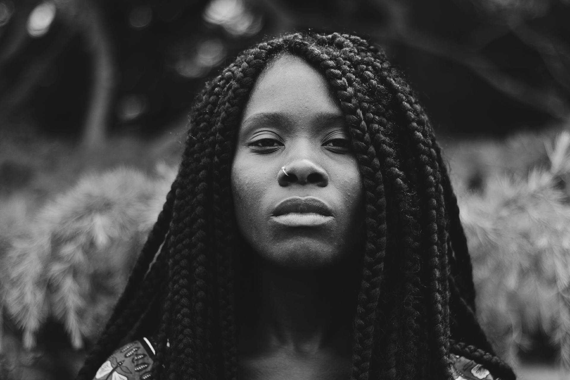 Striking black and white portrait of a woman with braided hair, exuding confidence.
